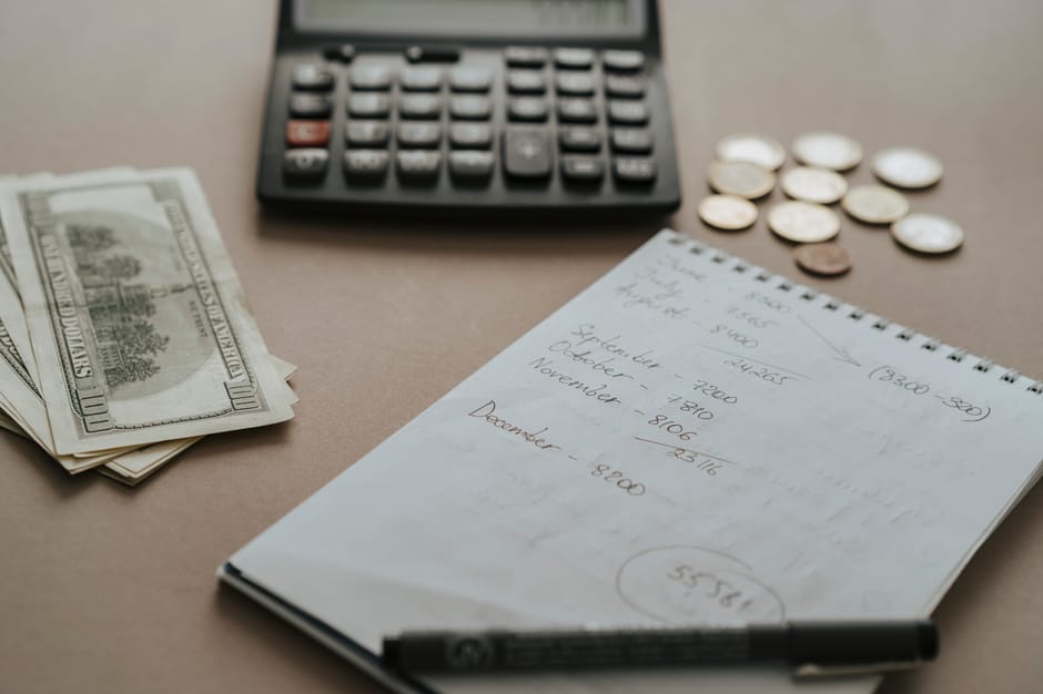 Average cost of pet insurance per month household budget: a desk with a calculator, cash, coins, and a financial notebook, the kind of careful budget review where the average cost of pet insurance per month gets compared against expected annual veterinary spending and household emergency reserves