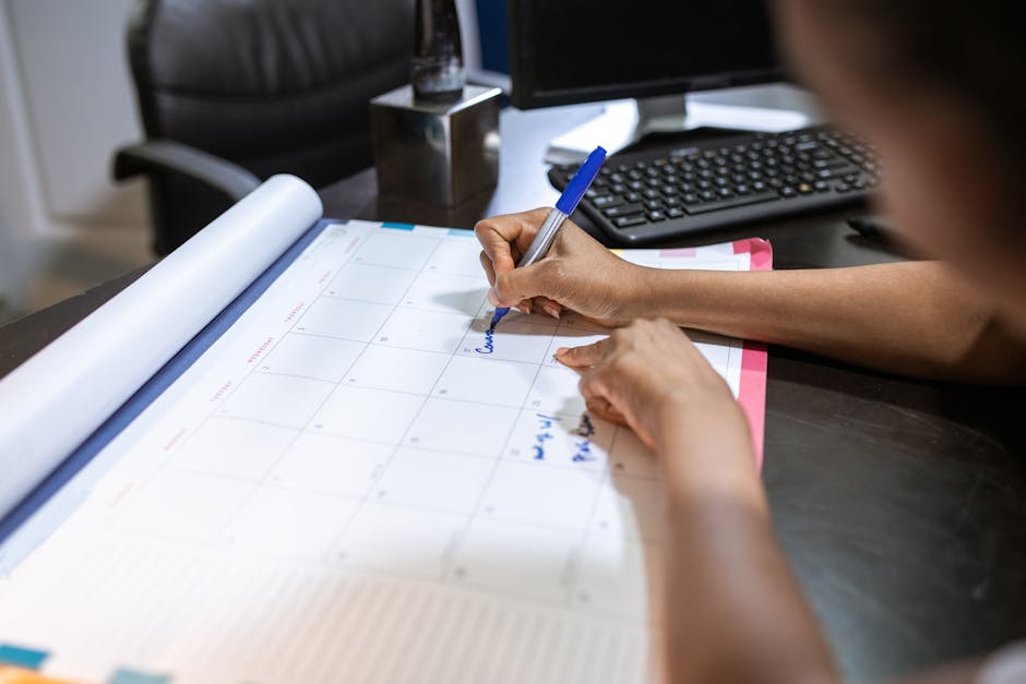 Pet insurance waiting period planning at the desk: a close-up of a woman writing on a desk calendar in an office setting, the kind of careful enrollment-timing exercise where the pet insurance waiting period gets mapped against the next 90 days of veterinary appointments